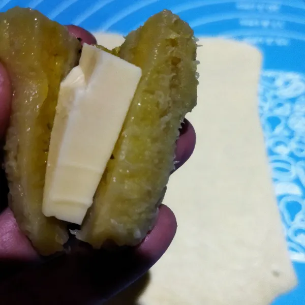 Belah tidak putus pisang kemudian isi dengan potongan keju.