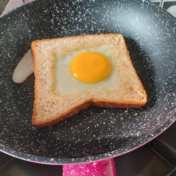 Panggang roti dengan api kecil dan tambahkan telur di tengah roti. Beri sedikit garam