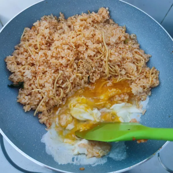Sisihkan nasi goreng ke tepi, tambahkan telur ayam, orak arik kemudian campur dengan nasi goreng. Masak sampai telur matang.