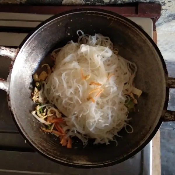 Masukkan mie jagung dan jamur kancing. Tumis hingga merata.