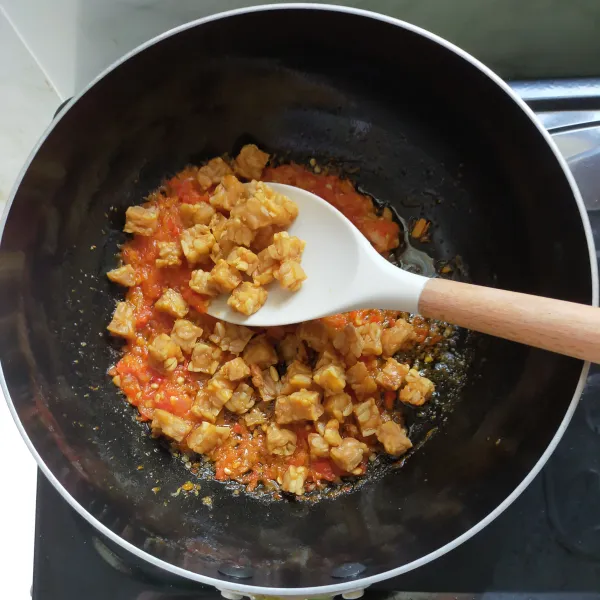 Kemudian masukkan tempe yang sudah digoreng, lalu beri air kaldu sapi, masak hingga mendidih.