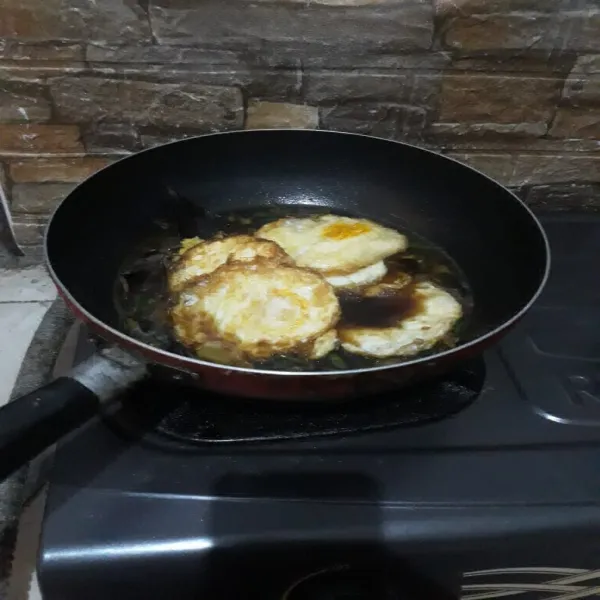 Lalu masukkan telur yang sudah diceplok, kemudian aduk rata, biarkan kuah menyusut dan bumbu meresap.
Angkat dan sajikan.