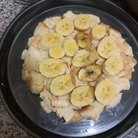 Siapkan loyang yang telah diolesi margarin, tata roti di atasnya tambahkan potongan pisang, ratakan.