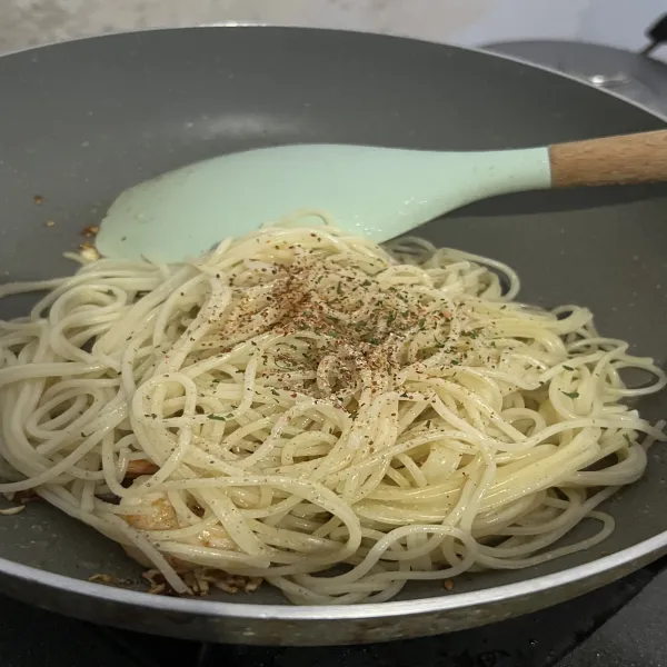 Setelah itu masukkan spaghetti, beri garam, merica, bubuk cabe, parsley, air lemon dan sedikit air rebusan pasta, lalu aduk sampai tercampur rata.