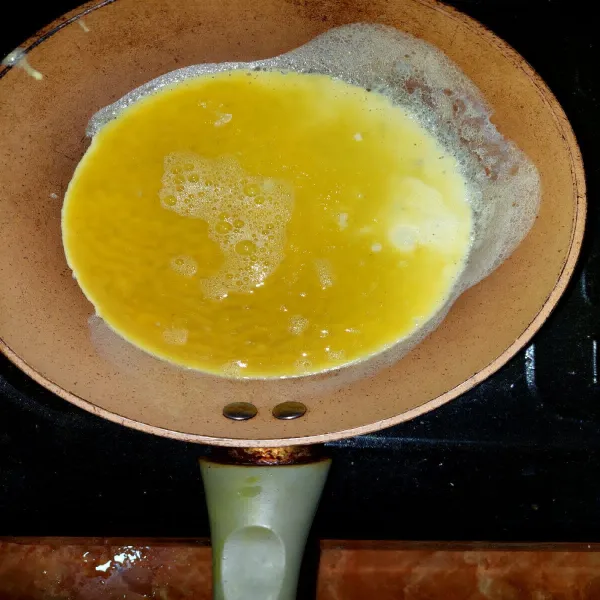 Panaskan sedikit margarin di atas teflon, lalu kecilkan api. Masukkan telur.