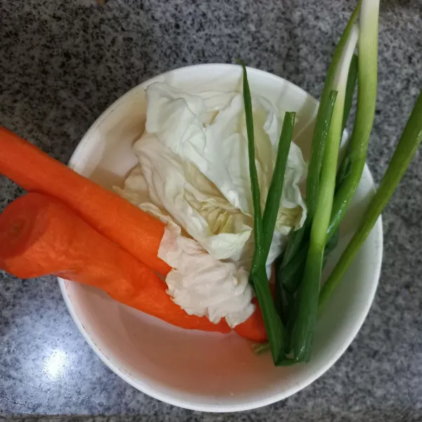 Kupas wortel, bawang daun dan kol.