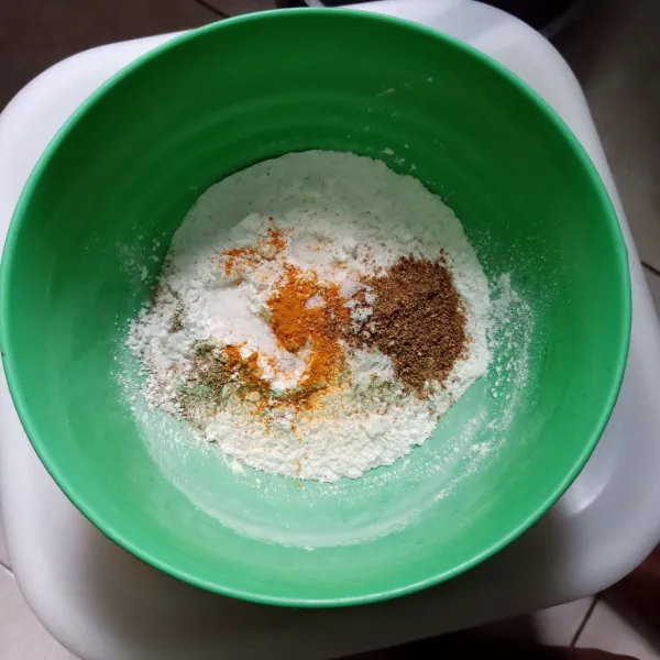 Campur tepung terigu, tepung beras, garam, kaldu bubuk, lada bubuk, ketumbar bubuk, dan kunyit bubuk dalam satu wadah.