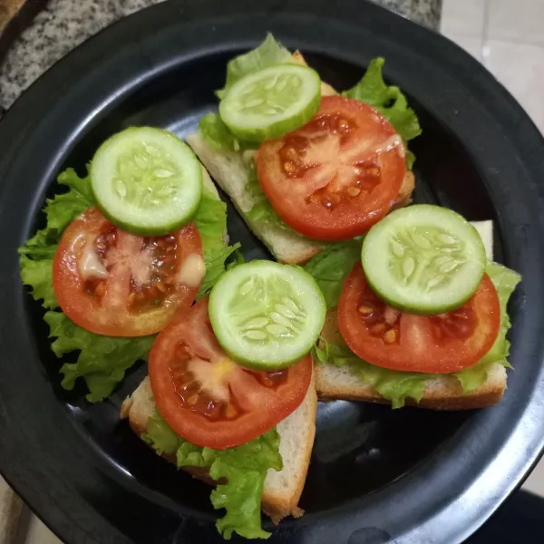 Siapkan potongan roti tawar, tambahkan daun selada tomat dan mentimun.