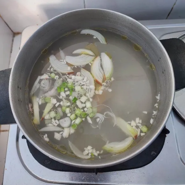 Masukkan bawang bombai, bawang putih, irisan daun bawang bagian putih dan jahe ke dalam sisa rebusan ayam.