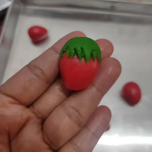Timbang adonan merah dengan berat 8 gram, bulatkan lalu bentuk seperti strawberry, ambil sedikit adonan hijau pipihkan lalu bentuk seperti daun lalu letakkan di atas adonan merah.