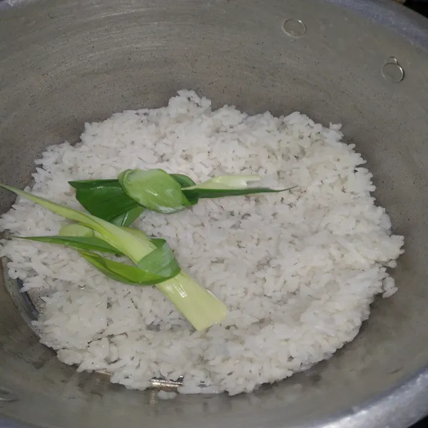 Masukkan nasi dan daun pandan ke dalam panci.