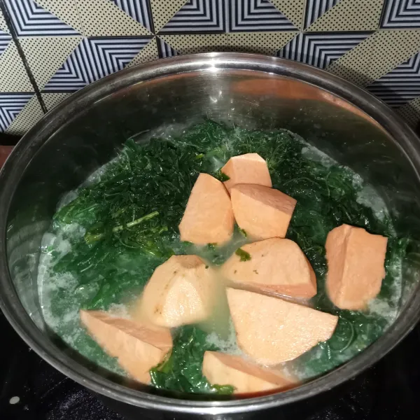 Rebus santan encer sampai mendidih, lalu masukkan daun singkong dan ubi .