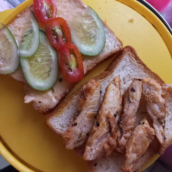 Iris tipis ayam panggang, kemudian tata di atas roti. Oleskan saus thousand island pada roti lainnya dan tata sayuran di atasnya. Kemudian siap disajikan.