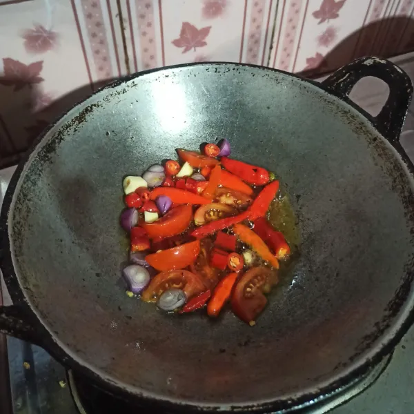 Goreng bahan sambal cabai, bawang merah, bawang putih, dan tomat hingga layu.