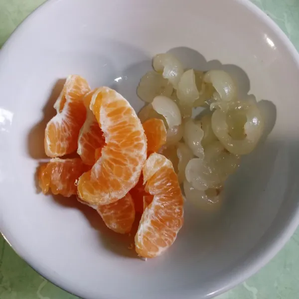 Kupas kelengkeng dan jeruk, lalu buang bijinya.