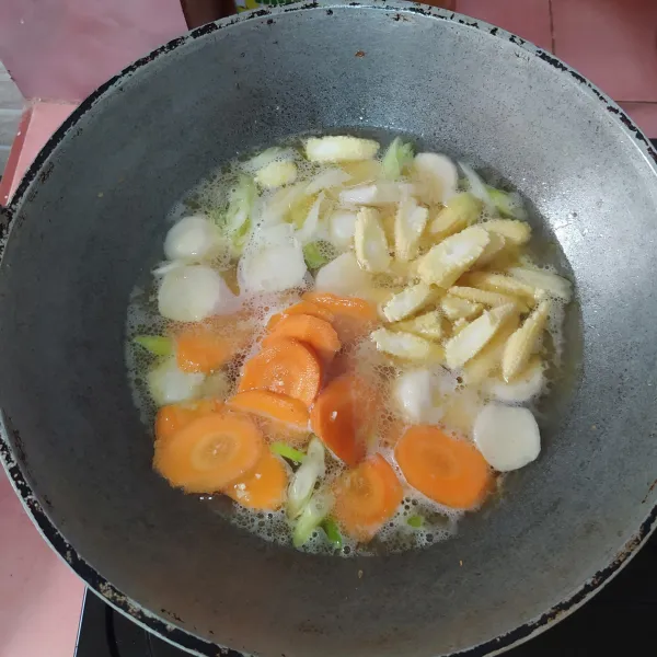 Masukkan irisan daun pre, lalu tuang air. Setelah air mendidih, kemudian masukkan wortel dan jagung muda.