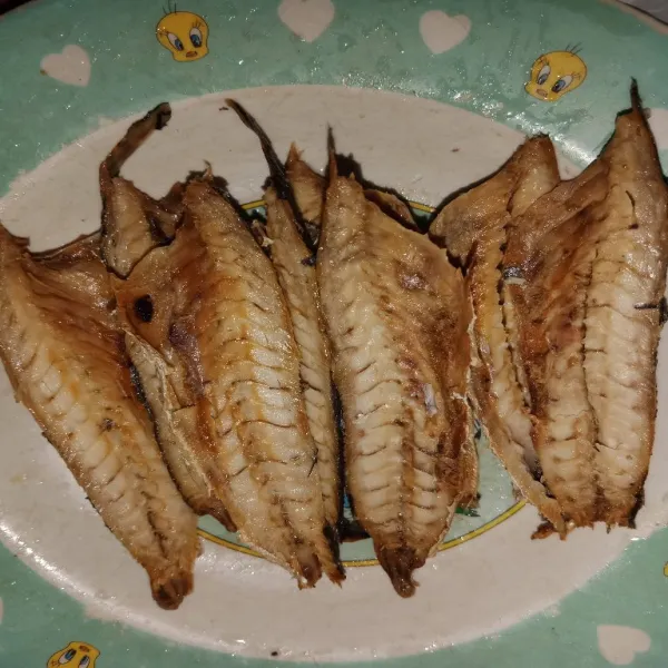 Belah ikan yang sudah digoreng menjadi 2 bagian.