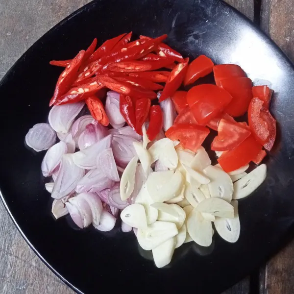 Iris tipis bawang merah dan bawang putih, kemudian potong-potong cabai dan tomat.