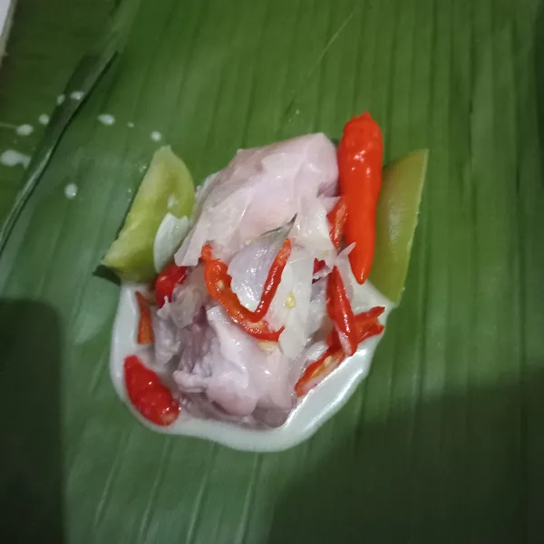 Siapkan daun pisang yang sudah dibakar agar lunak, lalu taruh ayam dan kucuri dengan beberapa sendok bumbu santan. Lakukan hingga bahan habis.