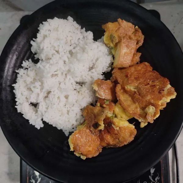 Tata nasi putih di atas piring saji, kemudian beri telur dadar tahu di atasnya.