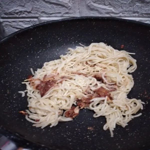 Ketika kornet mulai sedikit mengering dan warnanya berubah jadi gelap, masukkan spaghetti dan tambahkan kaldu bubuk. Lalu masak spaghetti hingga matang.