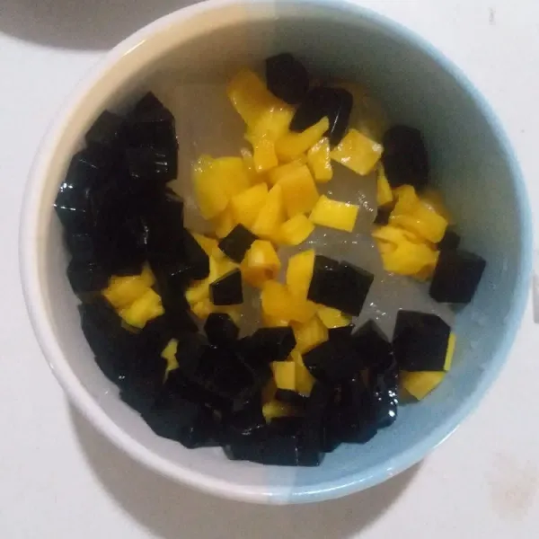 Masukkan potongan buah nangka, cincau hitam, selasih, dan sirup cocopandan. Lalu siram dengan air dan susu kental manis.