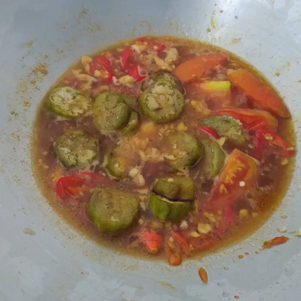 Tambahkan air dan terong goreng. Kemudian bumbui dengam garam, gula, merica bubuk, dan kaldu jamur. Koreksi rasa, masak sampai bumbu meredap.