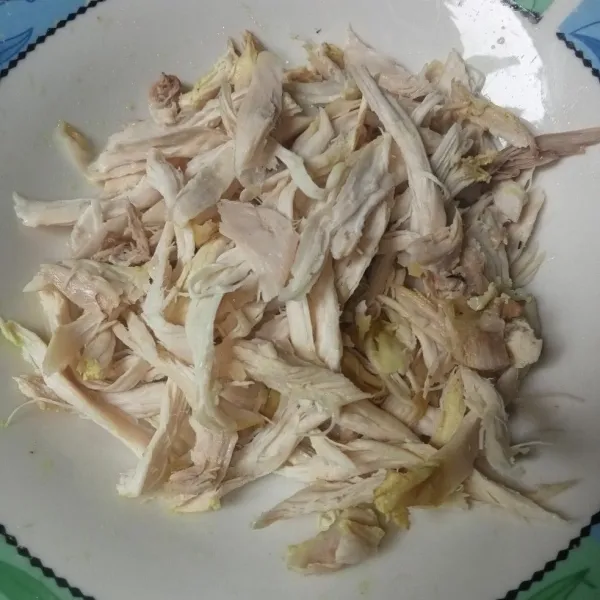 Suwir-suwir daging ayam, lalu sajikan ayam suwir dengan kuahnya beserta bahan pelengkapnya.