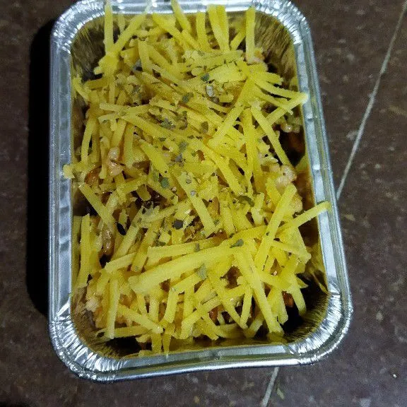 Selanjutnya tuang nasi goreng pada ramekin, beri keju parut dan taburi oregano.