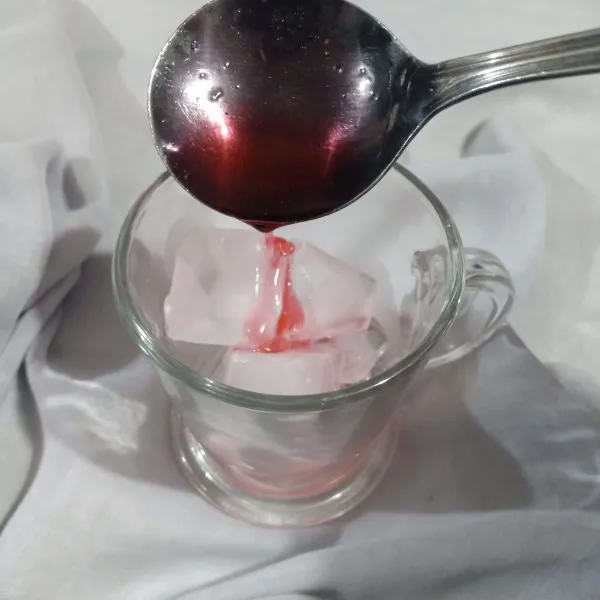 Siapkan es batu dalam gelas lalu beri syrup cocopandan.