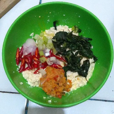 Masukkan bumbu halus, bumbu iris, daun kemangi, garam, dan kaldu jamur dalam wadah tahu. Kemudian aduk rata.