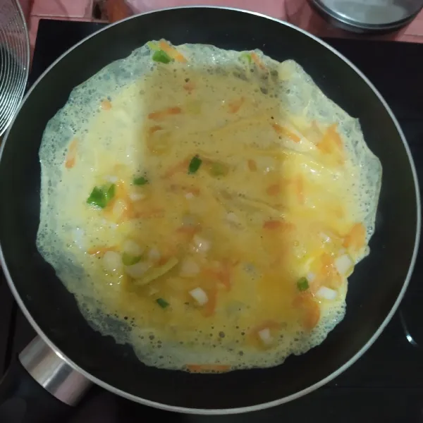Panaskan frypan, olesi sedikit minyak, lalu tuang ⅓ bagian telur.