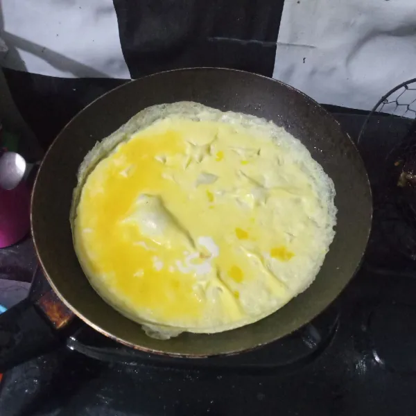 Panaskan sedikit minyak di wajan, tuang setengah bagian telur kocok. 
Ratakan, dadar hingga matang. 
Angkat.