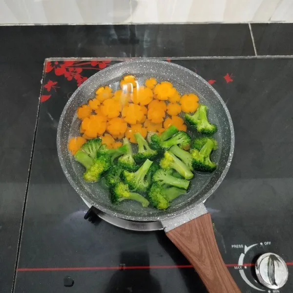 Rebus brokoli dan wortel dalam air mendidih hingga setengah matang, lalu angkat dan tiriskan.