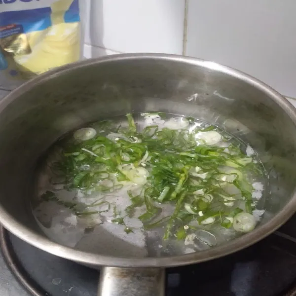 Dalam panci, rebus air bersama garam, gula putih, merica bubuk, penyedap rasa dan daun bawang hingga mendidih.