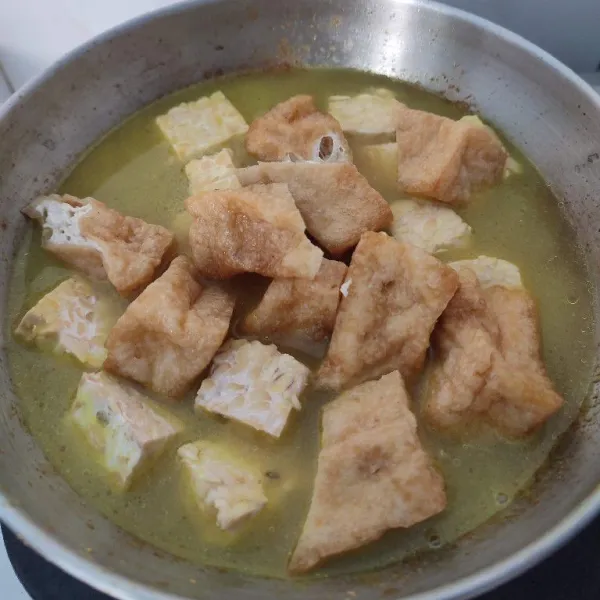 Masukkan tahu tempe dan air. 
Aduk rata, masak sampai mendidih.