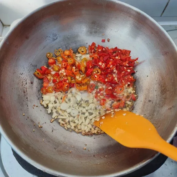 Masukkan cabe rawit dan cabe merah besar, tumis sampai bau langunya hilang.