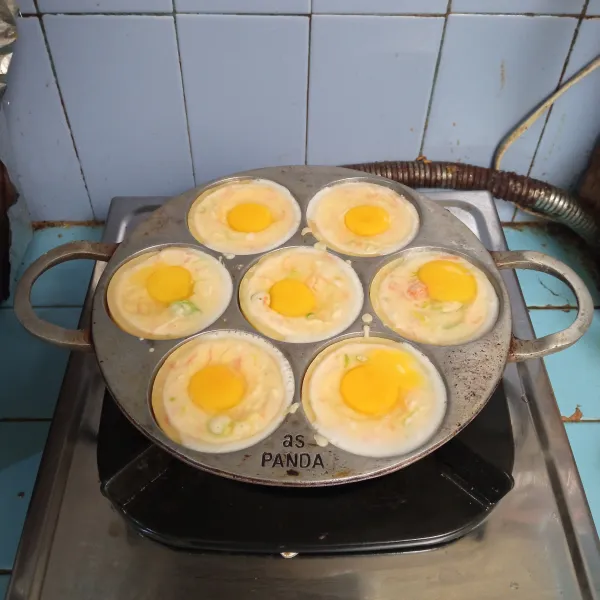 Tuang tiga sendok sayur, biarkan hingga setengah matang, lalu tambahkan telur puyuh di atas adonan. 
Panggang dengan api kecil.