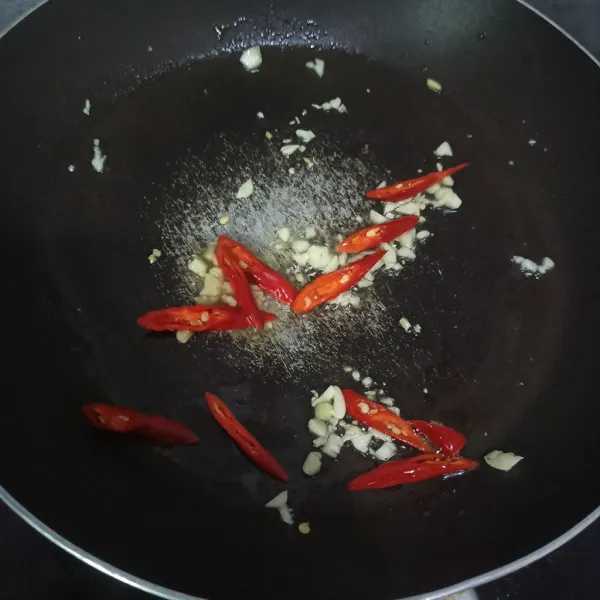 Tumis bawang putih dan cabe keriting hingga harum.