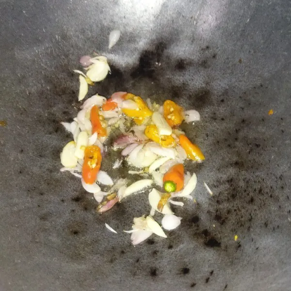 Panaskan minyak goreng, lalu tumis bawang merah dan bawang putih hingga harum. Kemudian masukkan cabai rawit.