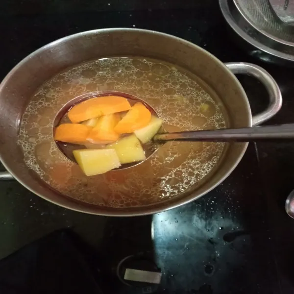 Panaskan minyak dalam panci, tumis jahe geprek, bawang putih dan bawang bombay, tumis hingga harum, lalu masukan air, wortel dan kentang, masak hingga wortel kentang lunak