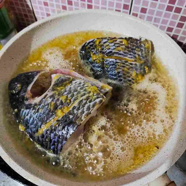 Panaskan minyak goreng, lalu goreng ikan nila hingga matang