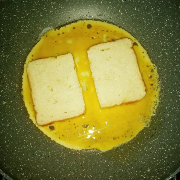 Letakkan roti selagi telur masih basah, beri jarak antar roti. 
Masak sampai telur set.