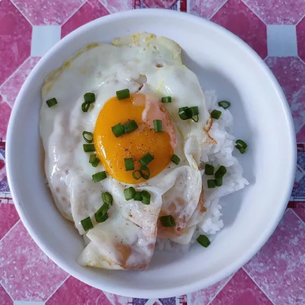 Letakkan telur ceplok di atas nasi, taburi dengan irisan daun bawang.