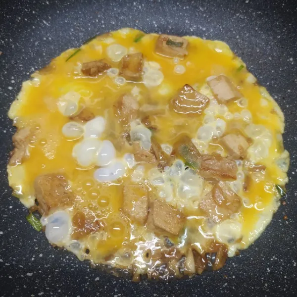 Tuang kocokan telur dan masak  dengan api kecil sampai telur matang. Kemudian angkat telur dan letakkan di atas mangkuk berisi nasi putih hangat. Beri taburan irisan daun bawang dan sajikan.
