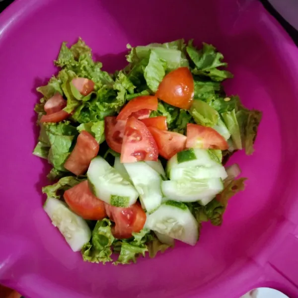 Masukkan selada dalam wadah, campurkan dengan potongan tomat dan timun