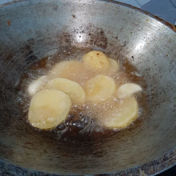 Goreng kentang dan bawang putih hingga empuk.