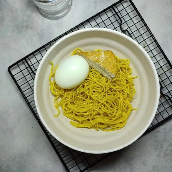 Pindahkan mie kuning ke dalam mangkok, kemudian beri telur dan tahu goreng.