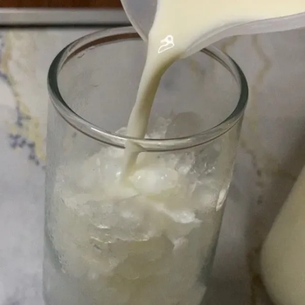 Masukan es batu kedalam gelas saji & tuang susu cair sampai 3/4 gelas.
