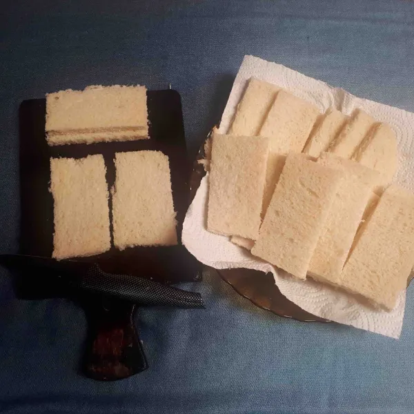 Siapkan bahan, potong bagian kulit roti yang kecoklatan, bagi jadi dua bagian.